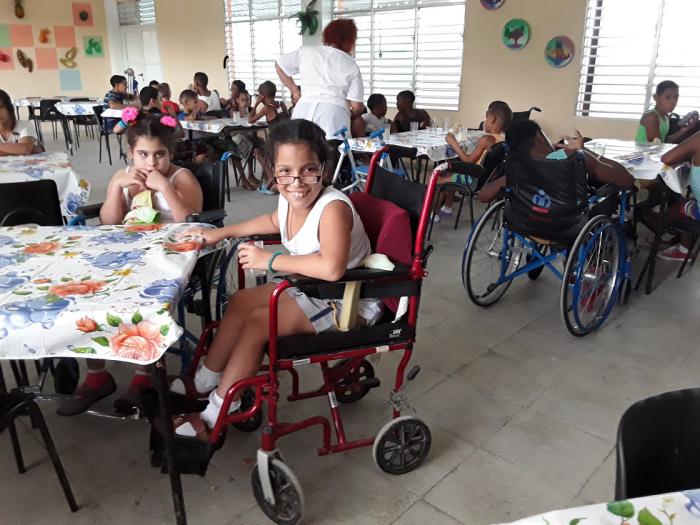 La pequeña Danais relee los Versos Sencillos de Martí a su paso en silla de ruedas frente a Villa Elvira. Foto: del autor La pequeña Danais relee los Versos Sencillos de Martí a su paso en silla de ruedas frente a Villa Elvira. Foto: del autor