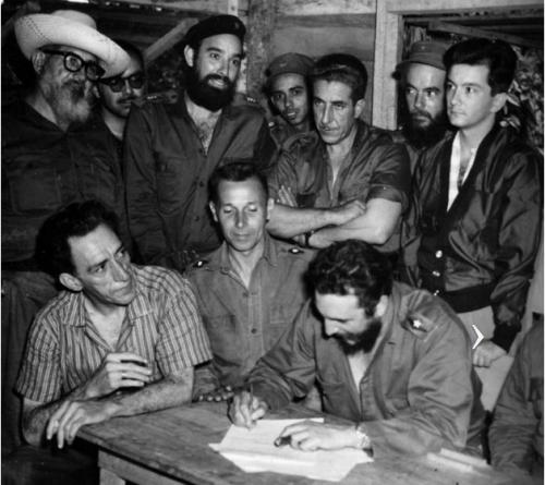 El Comandante en Jefe Fidel Castro firma la Ley de Reforma Agraria en la Comandancia de La Plata. A su derecha el médico Comandante Julio Martínez Páez, ministro de Salubridad, y Manuel Fernández, ministro de Trabajo. De pie, de izquierda. a derecha, el Comandante Crescencio Pérez, el Capitán Antonio Núñez Jiménez, el médico Comandante Manuel (Piti) Fajardo, Luis Orlando Rodríguez, ministro de Gobernación, el médico, Comandante René Vallejo, y el doctor Armando Hart Dávalos, ministro de Educación.
